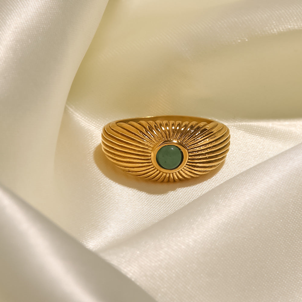 18K Gold Plated Green Stone Sun Ring displayed on satin fabric, featuring a sun-shaped design with a green stone.